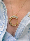 Coda Diamond Pendant in gold with a sculptural open C-shaped design and diamonds, worn on a model.