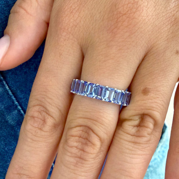 Baguette-cut natural tanzanite eternity ring with a sleek full-band design, shown worn on a hand for an elegant everyday look.