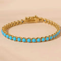 Sweet Mia Tempo turquoise cabochon bracelet with round turquoise stones set in gold on a soft beige background.