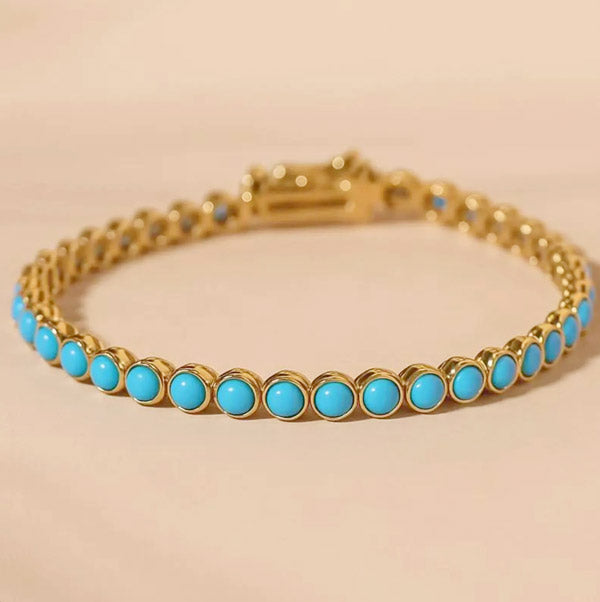 Sweet Mia Tempo turquoise cabochon bracelet with round turquoise stones set in gold on a soft beige background.